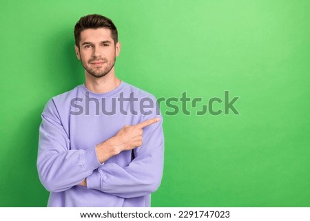 Photo of charming pretty young man wear purple smiling showing finger empty space isolated green color background