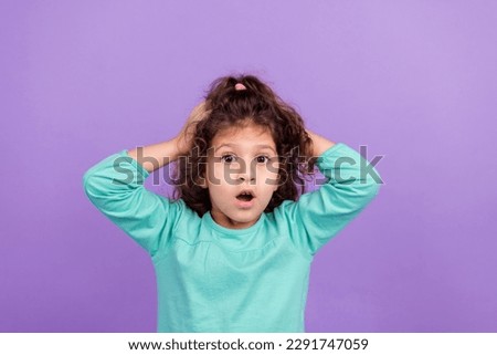 Photo of impressed funky little child dressed teal shirt big eyes arms head isolated violet color background
