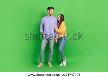 Full body portrait of two peaceful cheerful partners hug hold hands look each other isolated on green color background