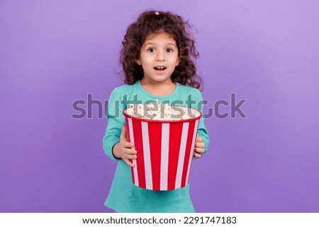 Photo of excited cheerful small kid wear turquoise shirt eating pop corn enjoying movie isolated violet color background