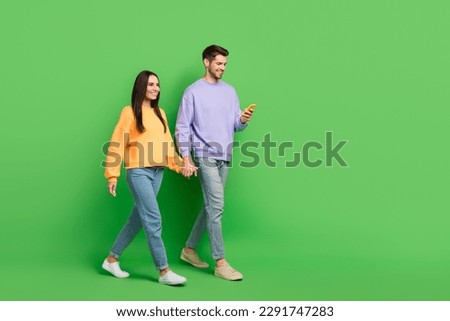 Full size profile portrait of attractive lady handsome guy use telephone hold hands walk empty space isolated on green color background Royalty-Free Stock Photo #2291747283
