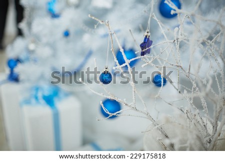 White Christmas tree with a blue toy, garlands, beads, boxes, gifts