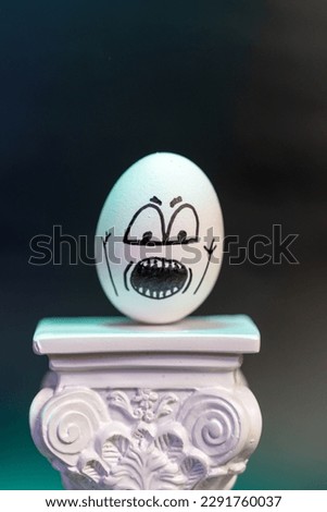 Animated egg with drawings of different faces and expressions mounted on a column in a large photograph