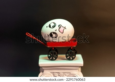 Animated egg with drawings of different faces and expressions mounted on a column in a large photograph