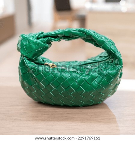Green, mini leather round hand bag is on the table
