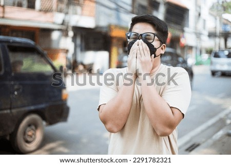 Asian man wearing face mask protect filter against air pollution (PM2.5) and Car pollution on street. Anti smog and virus. Air pollution caused health problem. Environmental pollution concept. Royalty-Free Stock Photo #2291782321