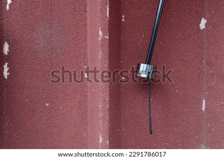 A black umbrella handle with a silver umbrella grip hanging on the wall.