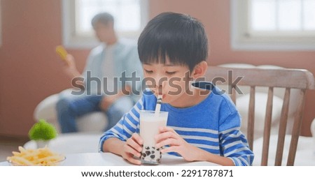 side view of asian children eat unhealthy high calorie sugary junk food such as french fries and bubble tea - father is scrolling his mobile with careless on the boy Royalty-Free Stock Photo #2291787871