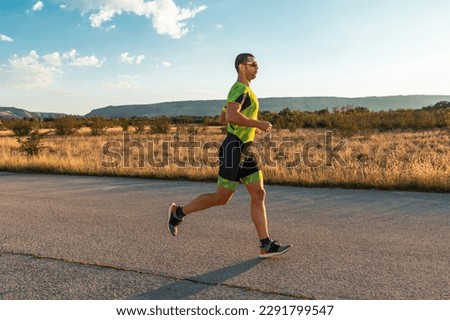 Triathlete in professional gear running early in the morning, preparing for a marathon, dedication to sport and readiness to take on the challenges of a marathon.  Royalty-Free Stock Photo #2291799547