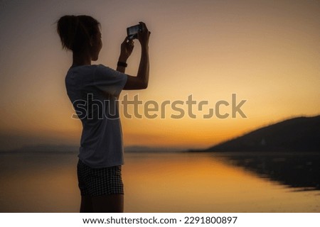 Woman Taking Pictures of the Sunset on the Dam, silhouette