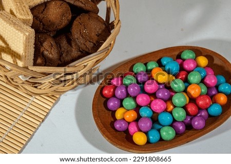 round colorful chocolate-flavored snacks on a mini wooden plate with a plain background as well as decorative snacks on a bamboo basket