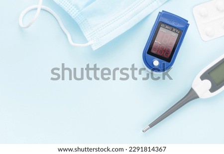 Medical kit for the prevention and treatment of coronavirus. Mask, test, pulse oximeter and medication on a blue background. Royalty-Free Stock Photo #2291814367