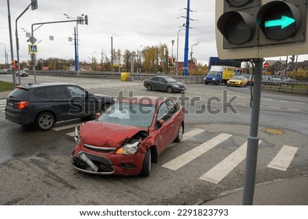 A red wrecked car stands at a crossroads against the backdrop of cars passing by. The concept of reckless and careless driving.                                Royalty-Free Stock Photo #2291823793