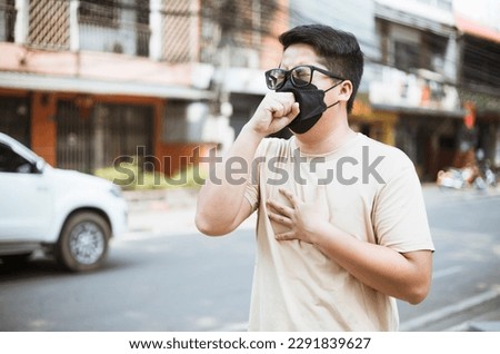Asian man wearing face mask protect filter against air pollution (PM2.5) and Car pollution on street. Anti smog and virus. Air pollution caused health problem. Environmental pollution concept. Royalty-Free Stock Photo #2291839627