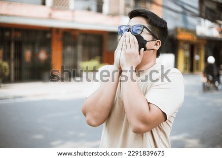 Asian man wearing face mask protect filter against air pollution (PM2.5) and Car pollution on street. Anti smog and virus. Air pollution caused health problem. Environmental pollution concept. Royalty-Free Stock Photo #2291839675