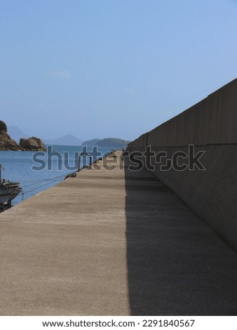 A view of inside of a breakwater.
A long straight breakwater of a fishing port.
A concrete structure to keep wave
entering into the port.
A landscape of Japanese fishing village. Royalty-Free Stock Photo #2291840567