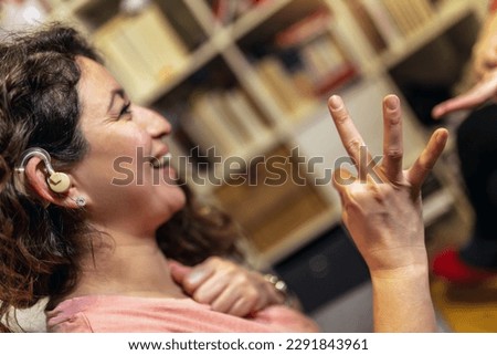 Deaf woman speaking sign language with her friend, sitting on couch. Royalty-Free Stock Photo #2291843961