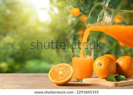 Pouring orange juice into the glass on wooden table in orange farming. Royalty-Free Stock Photo #2291845195
