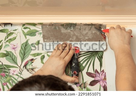 A worker pastes wallpaper on the walls in a room. Royalty-Free Stock Photo #2291851071
