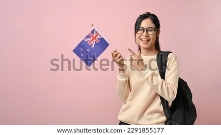 Confident pretty girl showing a New Zealand flag on pink isolated background, education concept. study abroad concept. Royalty-Free Stock Photo #2291855177