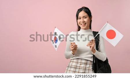 Happy young Asian woman showing Japan and South Korea flag on pink isolated background, education concept. study abroad concept. Royalty-Free Stock Photo #2291855249