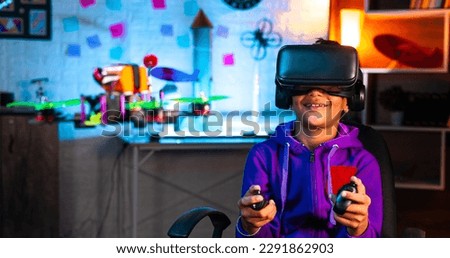 Intelligent indian kid controlling drone by wearing VR or virtual reality headset and controller at home - concept of modern technology, futuristic and innovation. Royalty-Free Stock Photo #2291862903