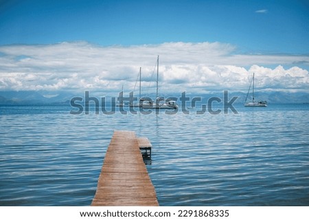 Boat sailing from the pier in the village. Blue lagoon with cloudy sky at the summer. Stock photo