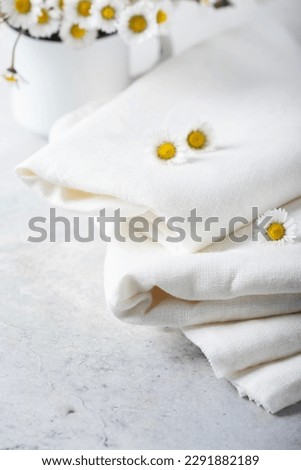 Concept of cozy home decor with wild daisy flowers and white linen tablecloth, selective focus image