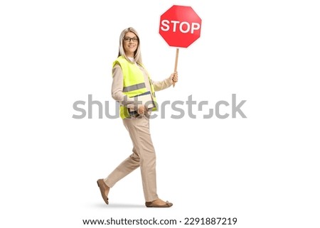 Full length shot of a young woman holding books and a stop sign and walking isolated on white background