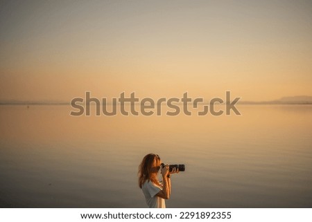 Woman Taking Pictures of the Sunset on the Dam, silhouette.