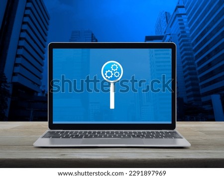 Seo icon on laptop computer screen on wooden table over modern city tower and skyscraper, Search engine optimization concept