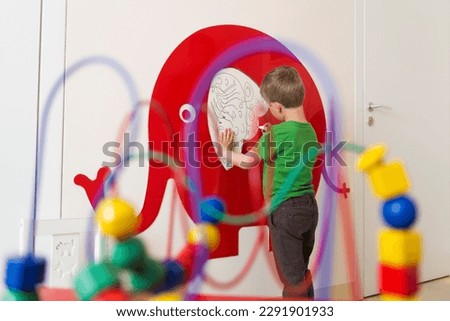 Colorful picture of a child drawing a big red elephant on the wall with colored pencils