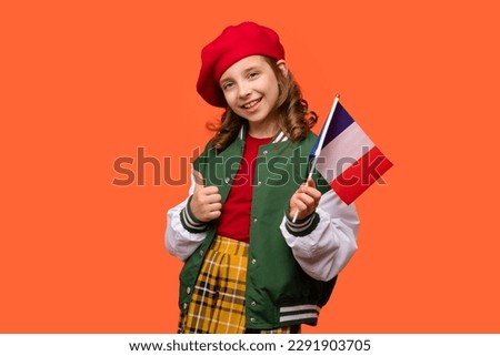 Girl wearing in school outfit and holds small national flag of France. Teen schoolgirl in red beret shows like, thumbs up, sign of approval