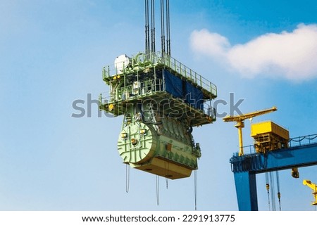 Transportation of a large marine engine by a port crane using steel cables. Royalty-Free Stock Photo #2291913775