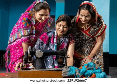 Portrait happy traditional indian woman wearing sari teaching other females how tu use sewing machine. Skill india Concept. Royalty-Free Stock Photo #2291926667
