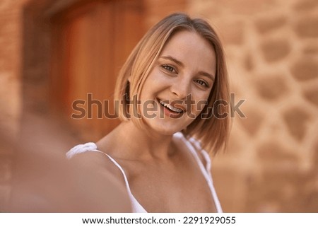 Young blonde woman smiling confident make selfie by camera at street