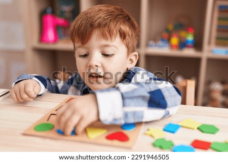 Adorable toddler playing with maths puzzle game sitting on table at classroom Royalty-Free Stock Photo #2291946505