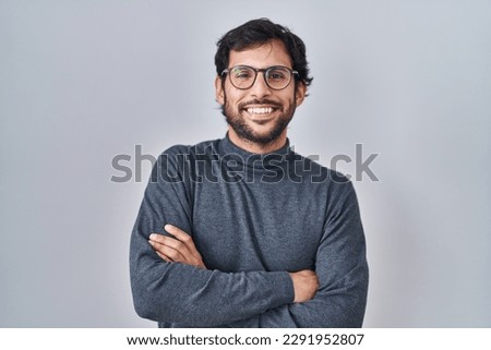 Handsome latin man standing over isolated background happy face smiling with crossed arms looking at the camera. positive person.  Royalty-Free Stock Photo #2291952807