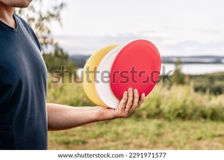 Disc golf. Discgolf or ultimate equipment. Park course and nature landscape. Throwing to target, goal or basket. Sport tournament. Hobby, training or fitness exercise. Green grass in the background.