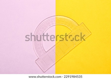 Transparent plastic protractor on color background