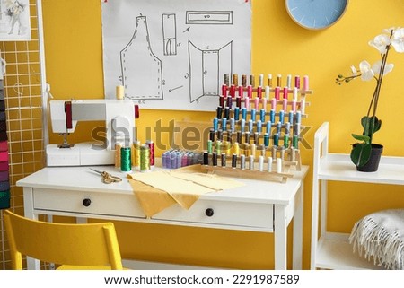 Tailor's workplace with sewing machine and thread spool in stylish atelier Royalty-Free Stock Photo #2291987589