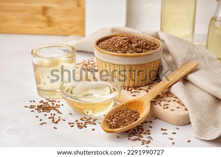 Bowl, glass with flax oil and spoon of seeds on white background Royalty-Free Stock Photo #2291990727