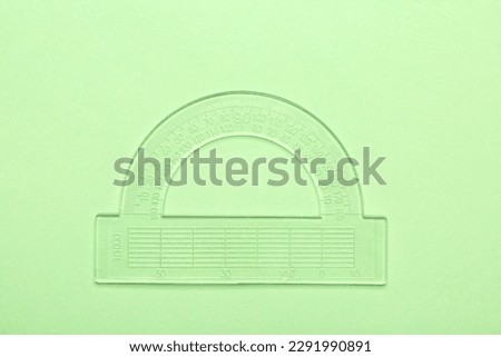 Transparent plastic protractor on green background