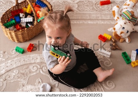Top view little girl sitting on a floor a with toys and playing with little car. Royalty-Free Stock Photo #2292002053