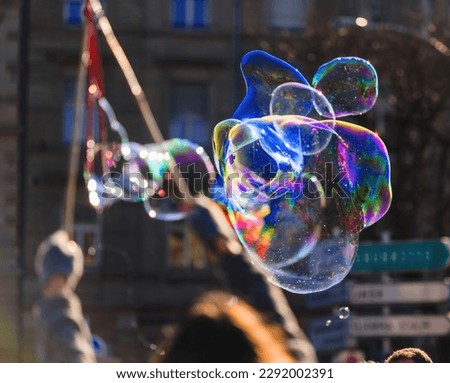 Adult hands stands in mid-air, joyfully blowing multi colored liquid bubbles with a bubble wand. The fragility of soapy balloons makes it an exciting experience Royalty-Free Stock Photo #2292002391
