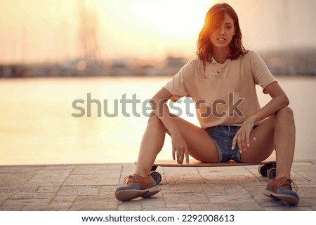 Young trendy female riding the skateboard on a sunny day