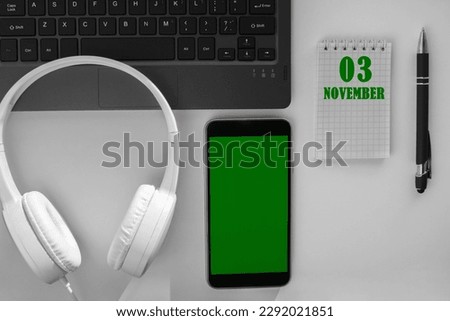 calendar date on a light background of a desktop and a phone with a green screen.  November 3 is the third  day of the month.
