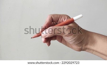 write with a pen.  the position of the hand writing with a orange marker