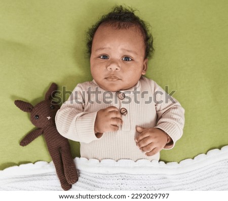 African american baby relaxing on bed with doll at bedroom