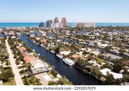 Aerial drone shot of the Coral Ridge neighborhood, in Fort Lauderdale, Miami, USA, commercial area, with canals and boats sailing, luxury houses and mansions, abundant tropical vegetation around, blue